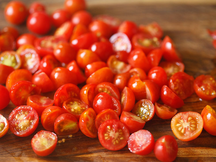 chopping larger cherry tomatoes.