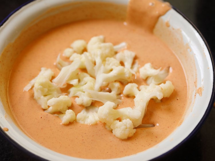 placing cauliflower florets in the batter