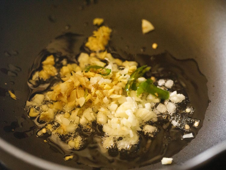 adding chopped garlic, ginger and slit green chillies to hot toasted sesame oil in a wok