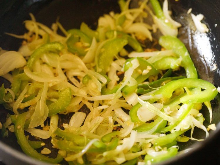 stir frying spring onions and capsicum in the wok