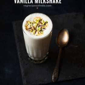 vanilla milkshake served in a glass. topped with chopped pistachios.
