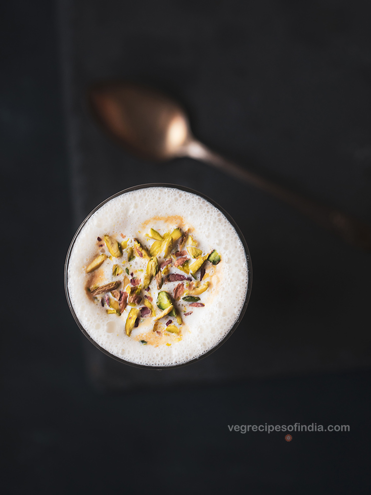 top shot picture of vanilla milkshake in a glass with a bronze spoon in the background