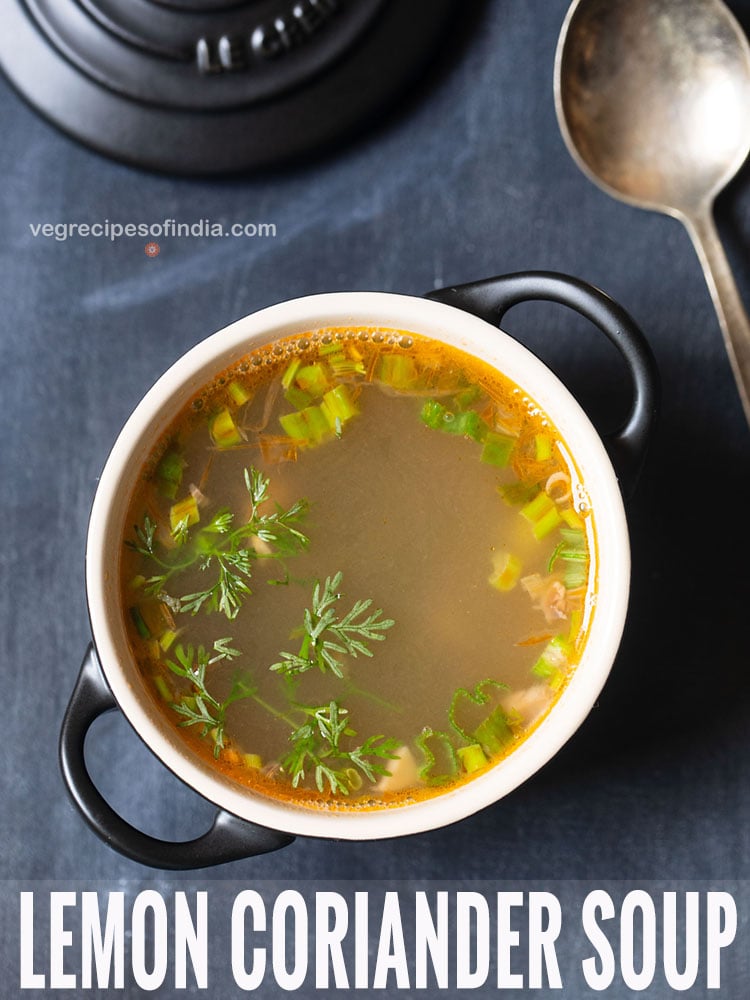 lemon coriander soup served in a black bowl with handles with a soup spoon on the side on a dark bluish grey background with text layovers.