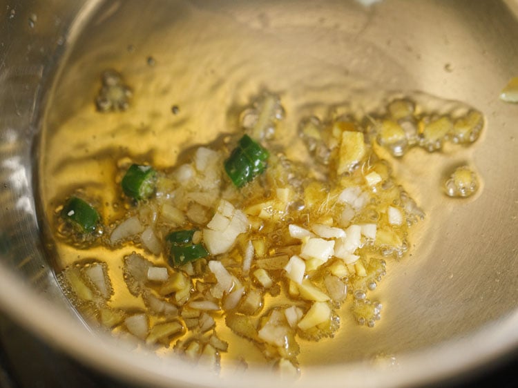 adding chopped ginger, garlic and green chillies in the hot oil.