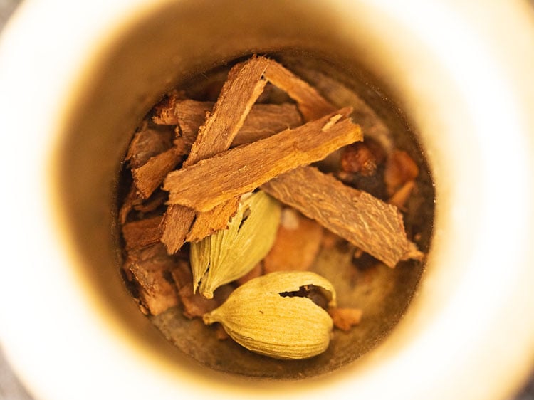 kahwa spices being crushed in a mortar-pestle.