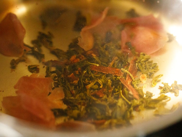 hojas de té verde añadidas al agua caliente después de retirar la sartén del fuego.