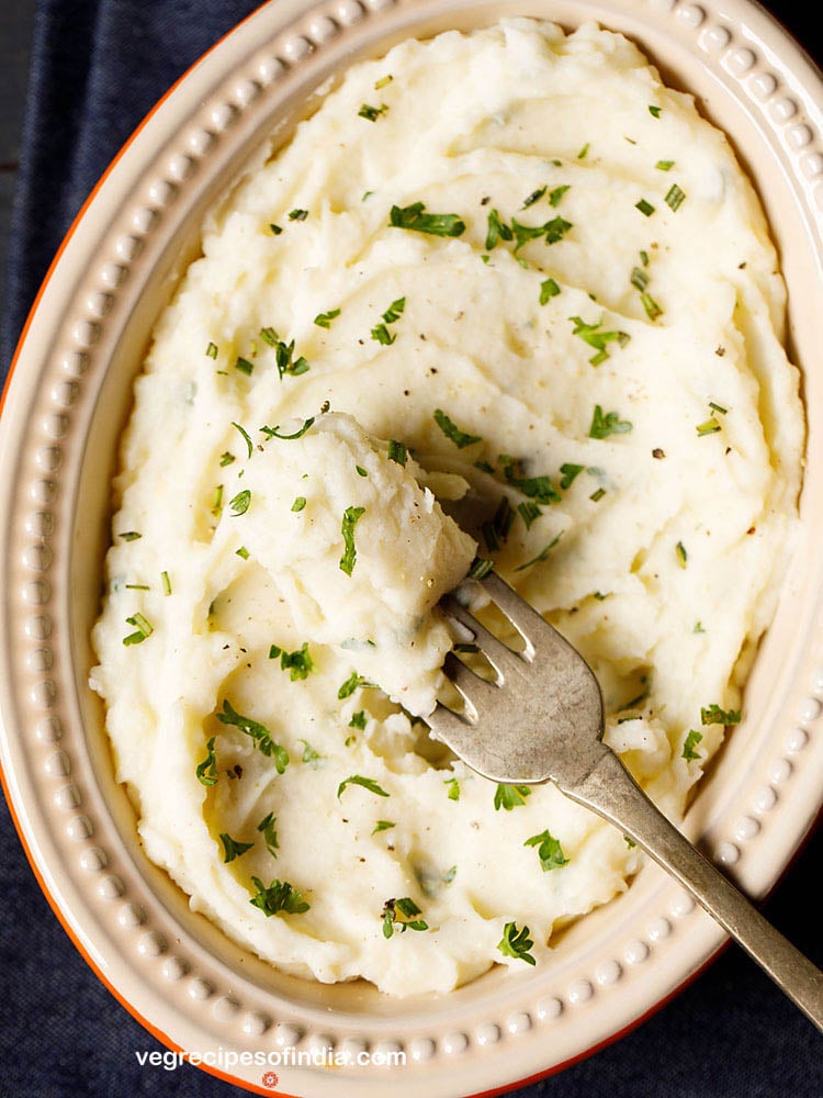 a portion of garlic mashed potatoes scooped with a fork from the bowl. 