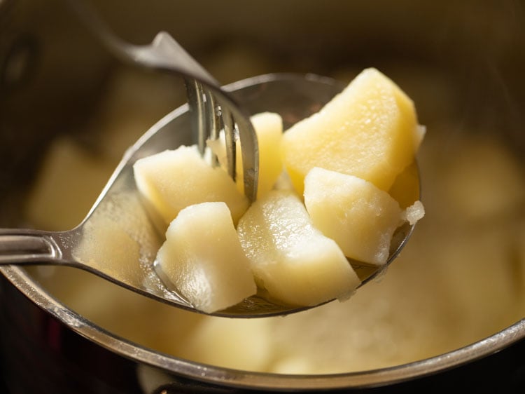 checking a few cooked potatoes by piercing fork through them