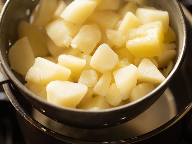 using a colander to strain the cooked potatoes