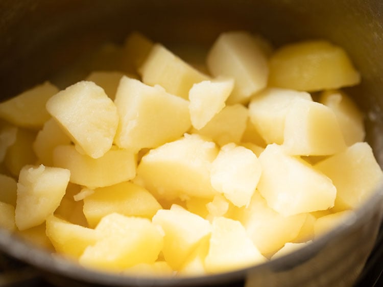 adding cooked potatoes to the milk, butter and garlic in the pan.