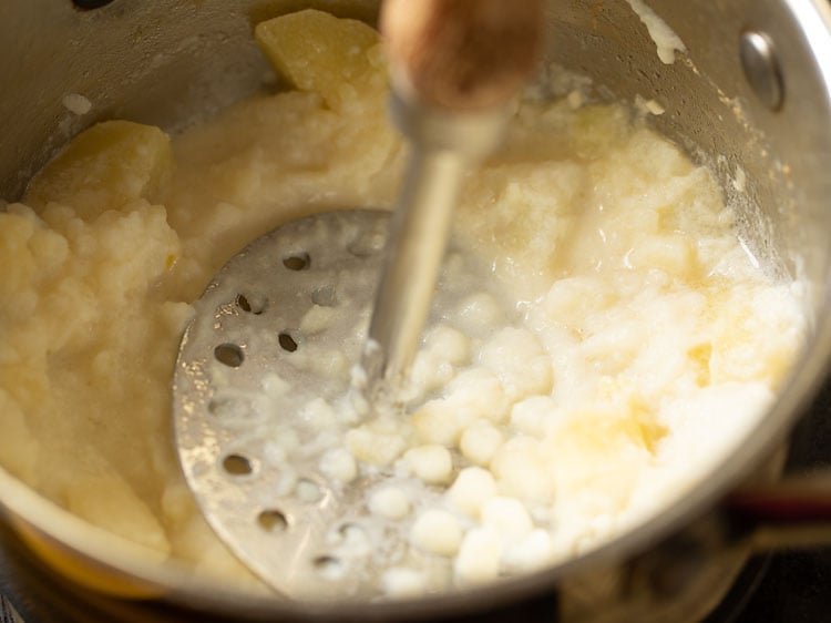 mashing potatoes with a hand masher.