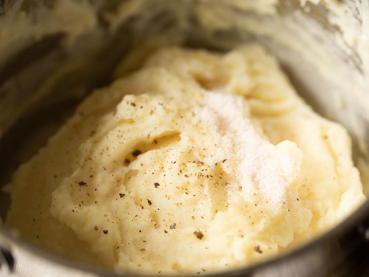 salt and black pepper sprinkled on mashed potatoes in the pan.