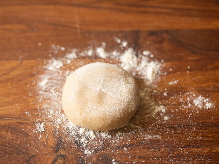 each sliced dough part rolled into a ball and then slightly flattened on rolling board with flour sprinkled over top. 