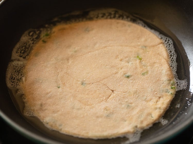 flatbread placed in hot oil in a frying pan.