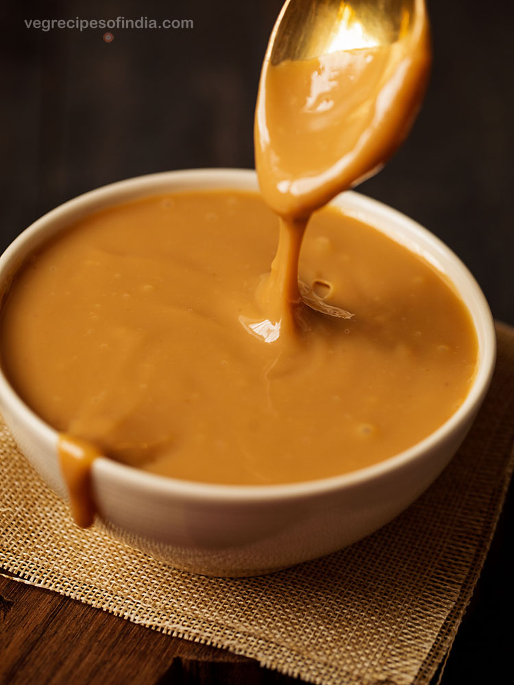 drizzle shot of dulce de leche in a white bowl with some spilling over the edge.