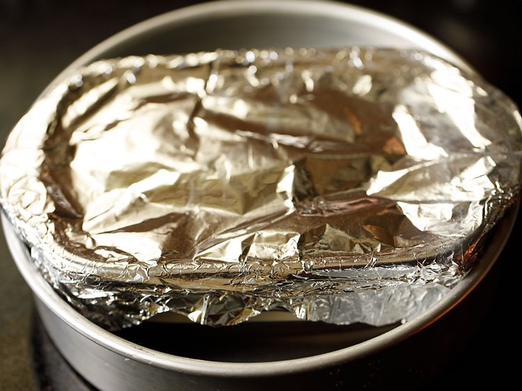 fitting covered pan inside a round baking tin.