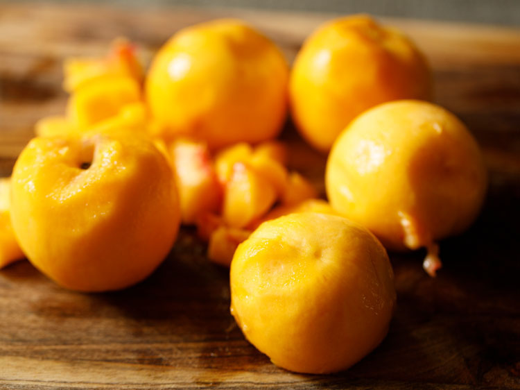 peeled peaches on a cutting board.