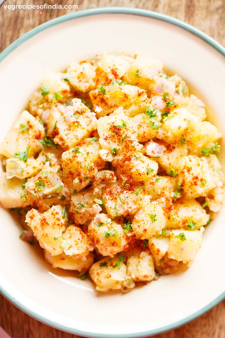 potato salad garnishesd with parsley, specks of paprika served in a cream enamel plate