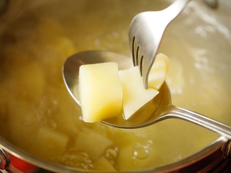 demonstrating how to check cooked potatoes with a fork.