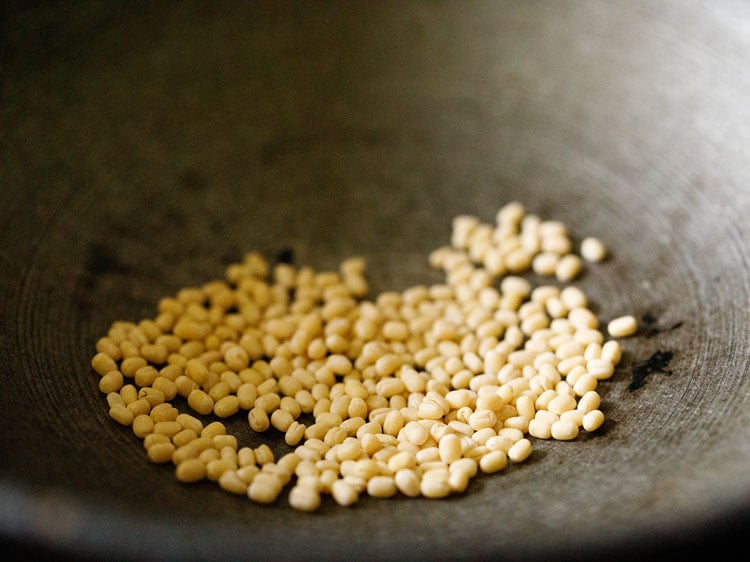 urad dal added in hot heavy pan for thattai recipe. 