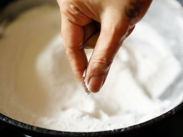 checking the rice flour while roasting to see if it's warm. 