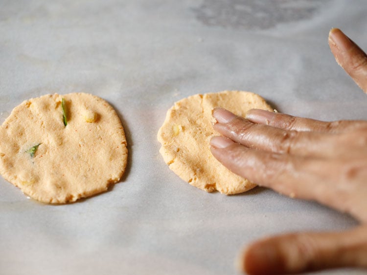 pressing the dough ball with fingertips, into a round thattai. 