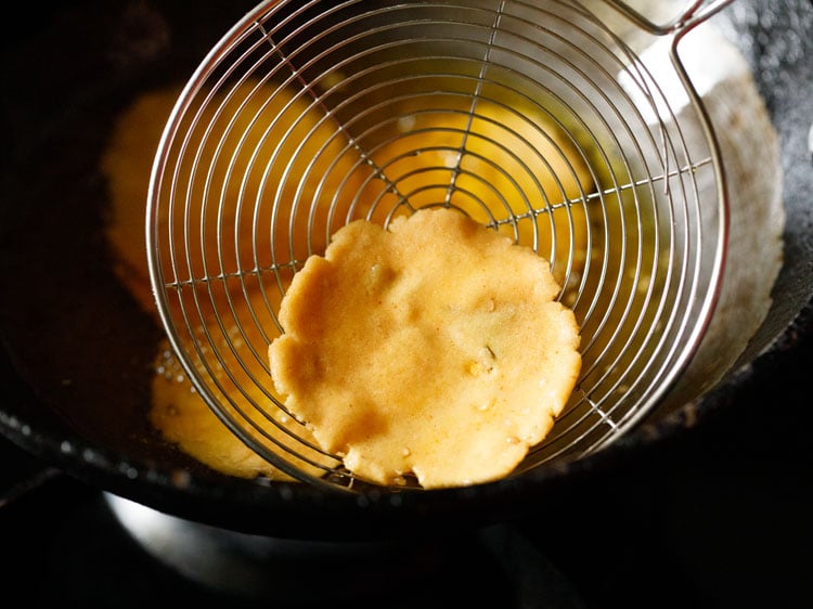 removing fried thattais from the oil using a slotted spoon. 