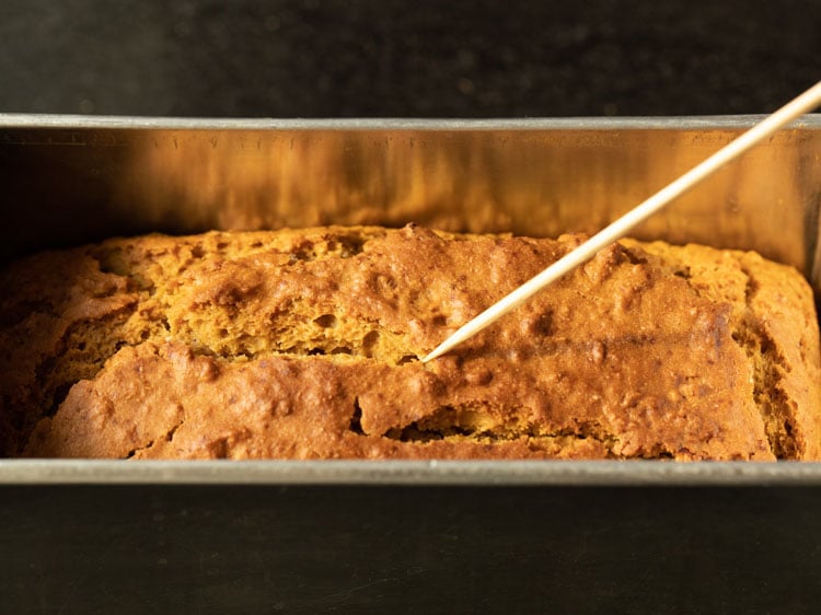 checking pumpkin bread with a wooden skewer.