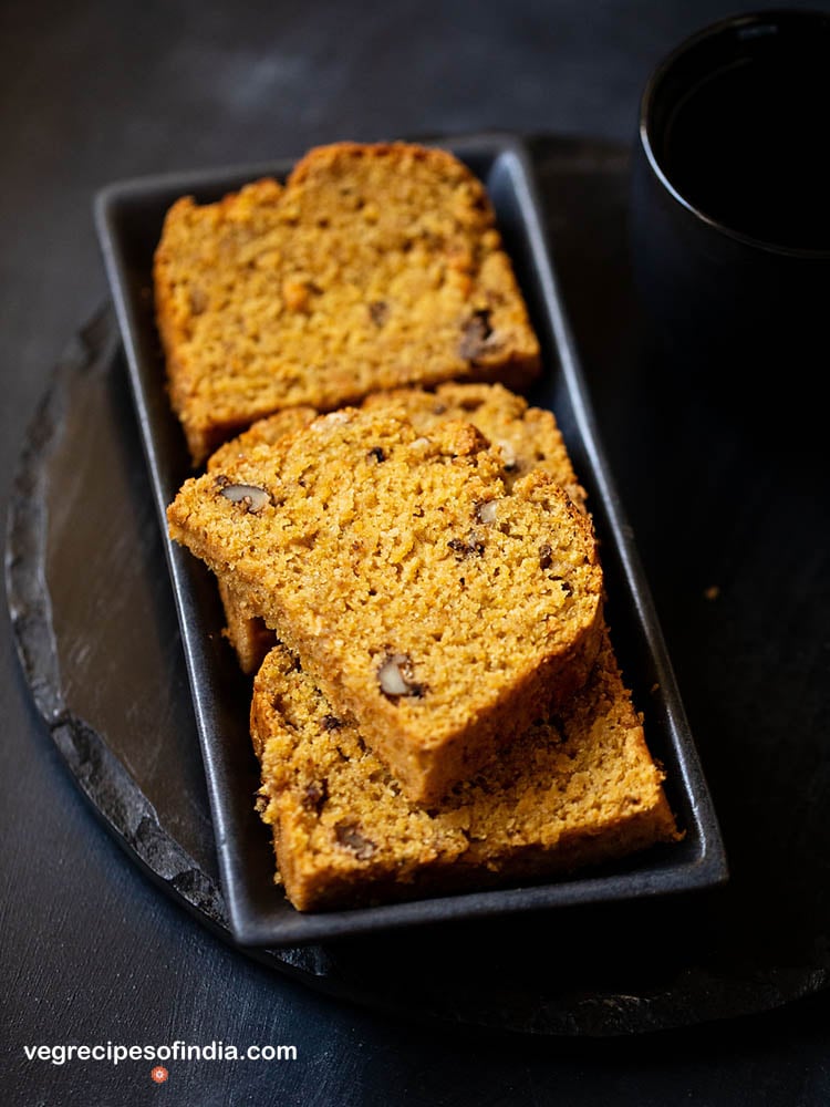 sliced pumpkin bread on black ceramic tray on a black slate board.