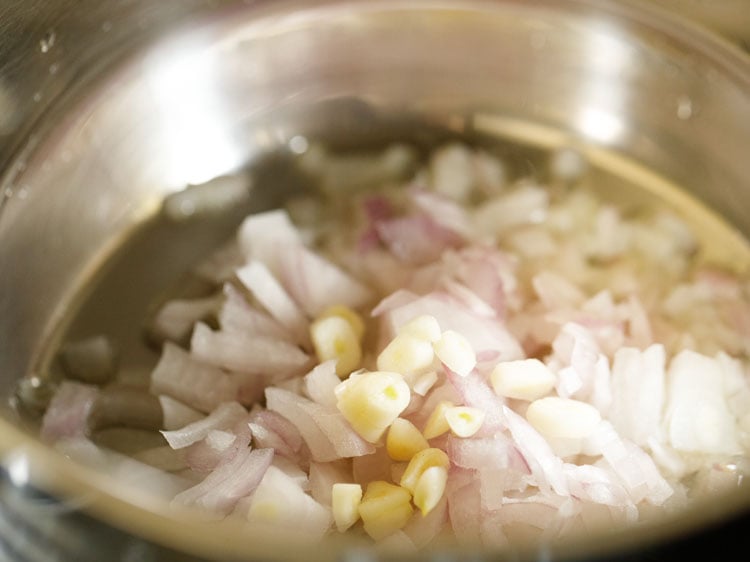 adding onions and garlic to hot oil in a pot