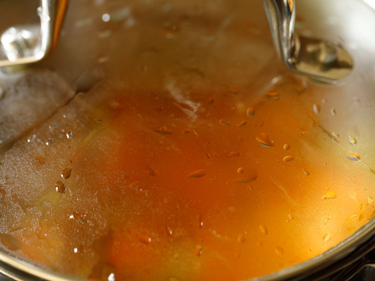 pot covered with lid and carrot soup mixture being simmered