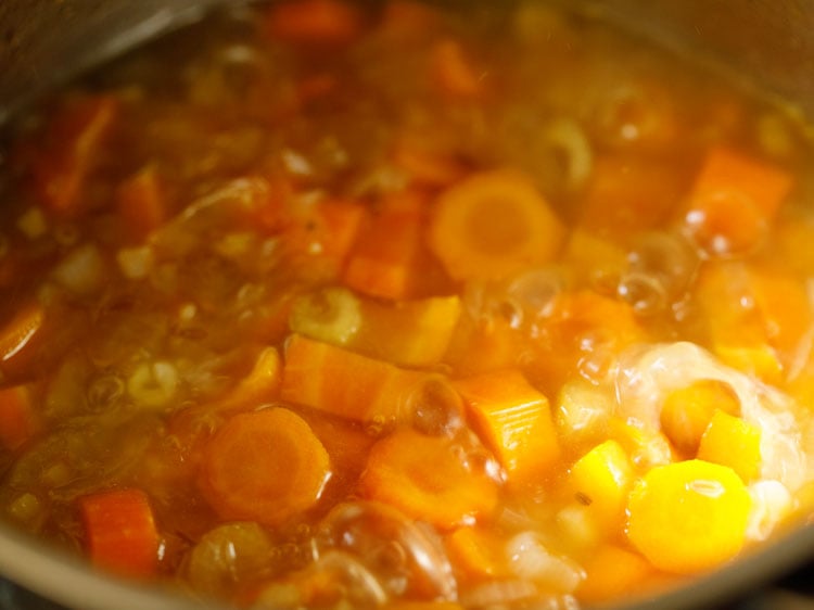 checking carrot soup mixture while simmering