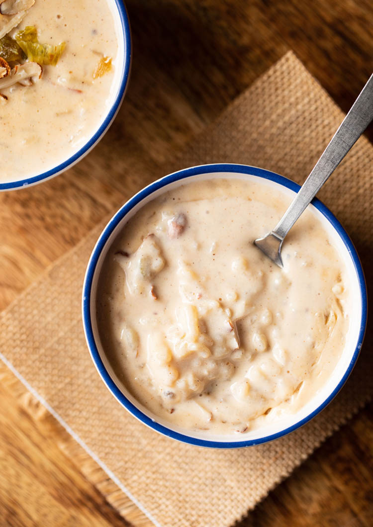 rice pudding in a blue rimmed bowl with a spoon in the bowl