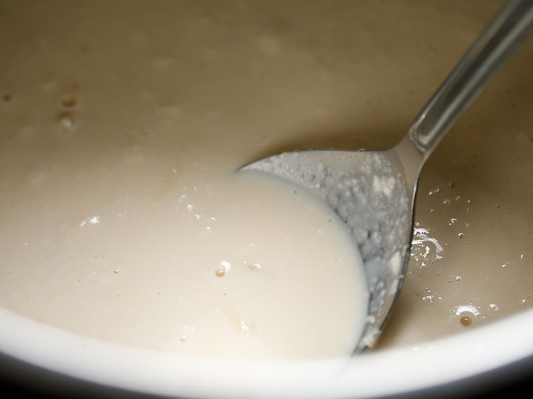 breaking a few rice lumps in the pudding using a spoon.