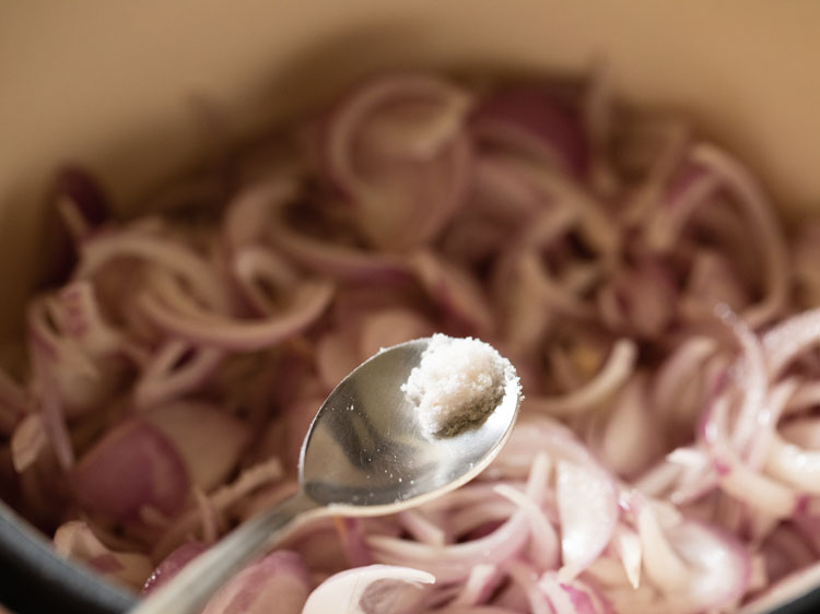 a pinch of salt being added to the onions.