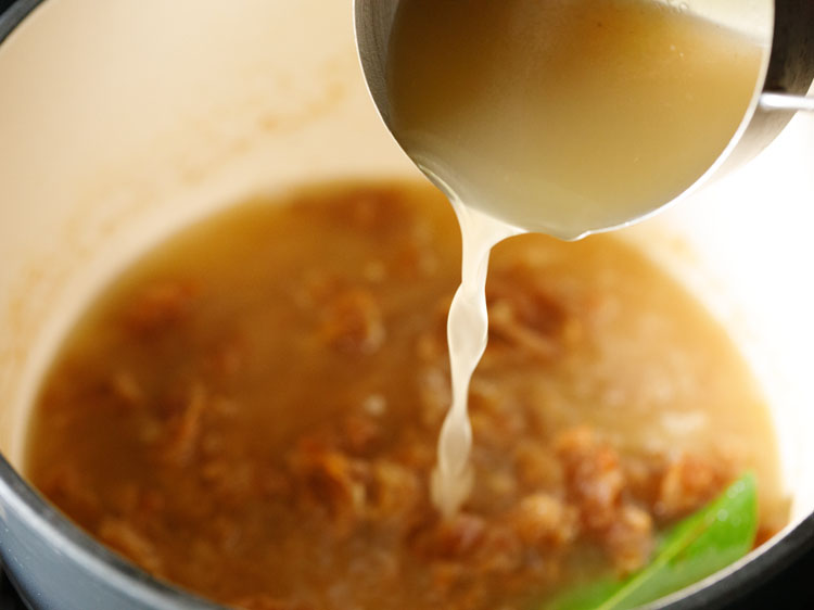 vegetable stock is being added to french onion soup.