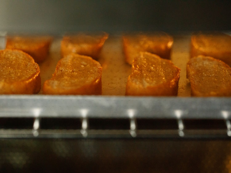 baguette slices being toasted in the oven.