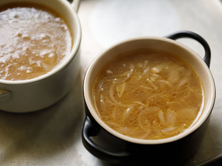 individual serving bowls with french onion soup in them.