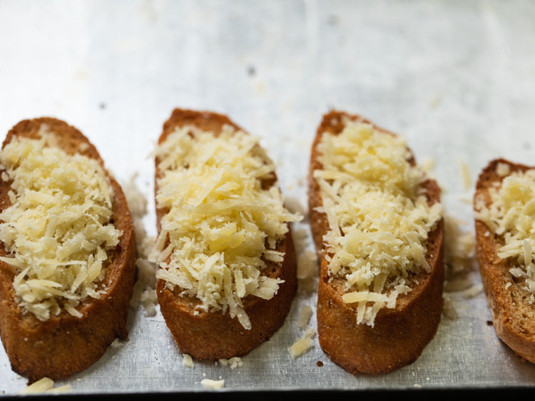 toasted baguette slices with grated gruyere cheese on them.