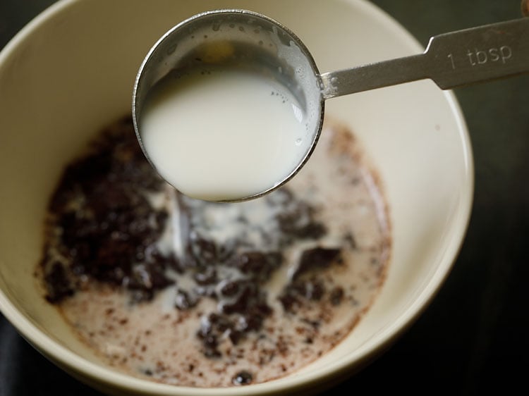 adding hot milk to the chopped chocolate in the bowl