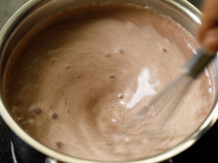 mixing melted chocolate and hot milk with wired whisk