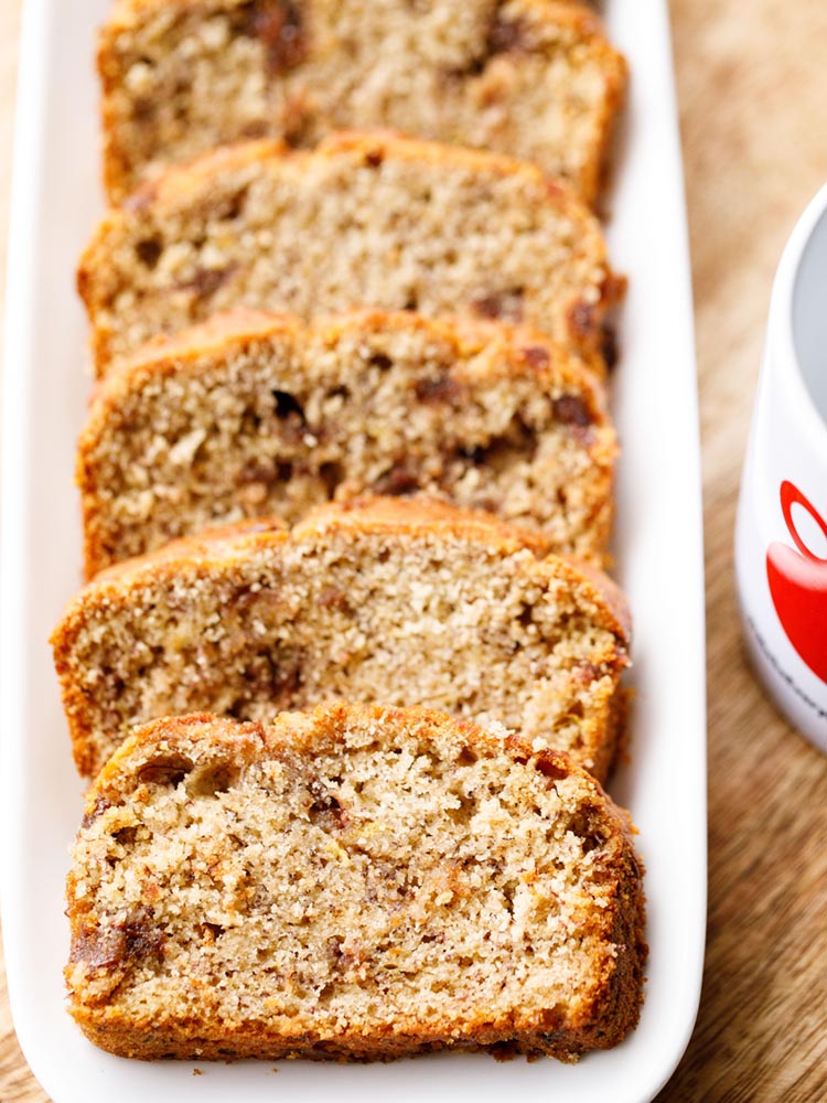 chocolate chip banana bread slices served on a white rectangular platter on a wooden board. 