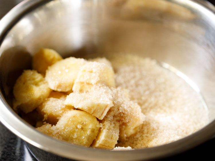 chopped bananas and sugar added in a mixing bowl. 