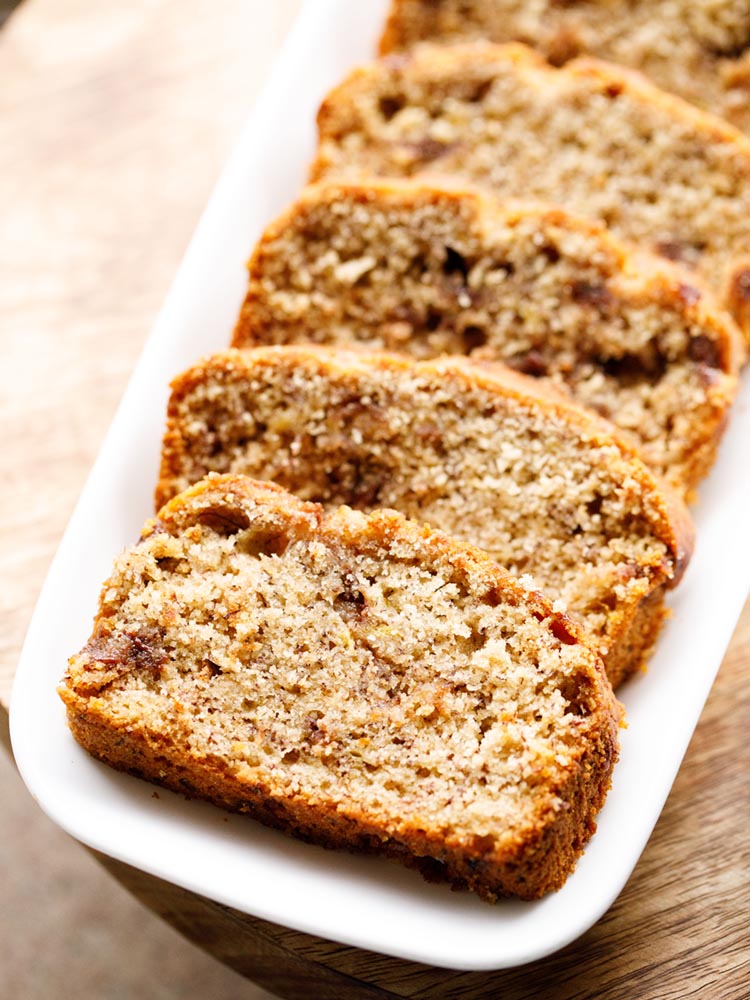 chocolate chip banana bread slices served on a white rectangular platter on a wooden board. 