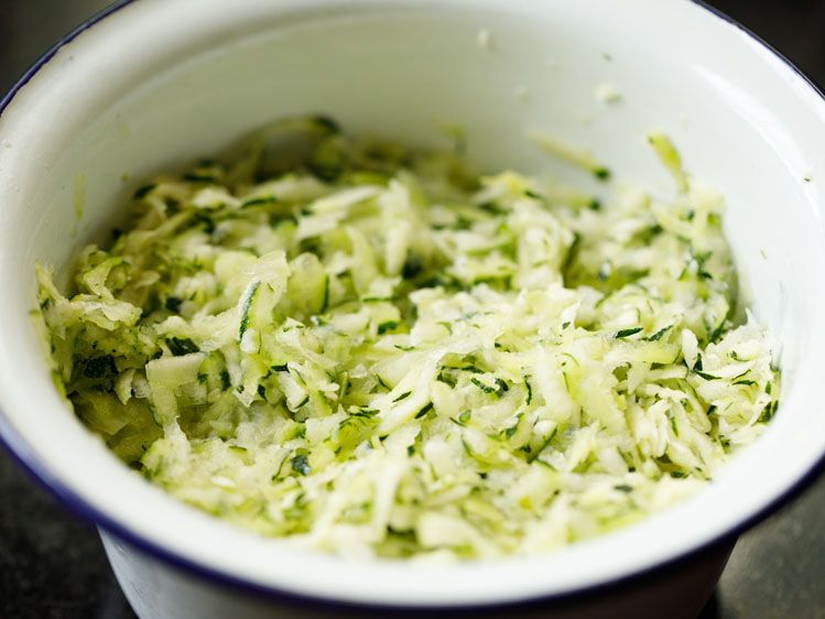 grated zucchini in a white mixing bowl.