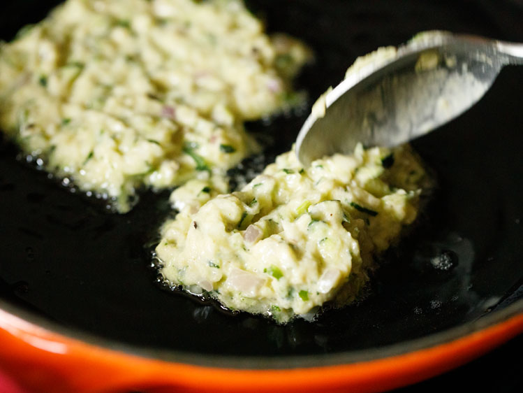 fritter batter from the spoon being poured in the pan.