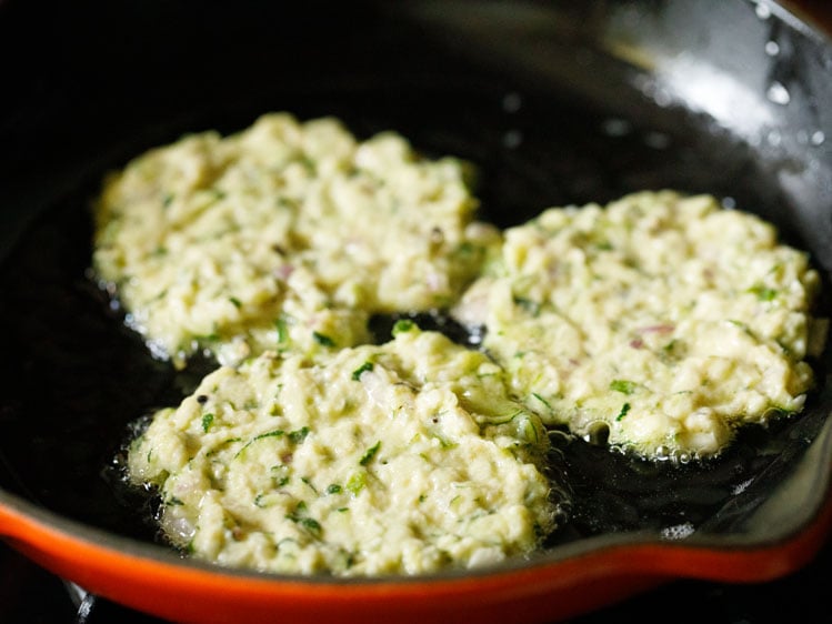 zucchini fritters being fried. 