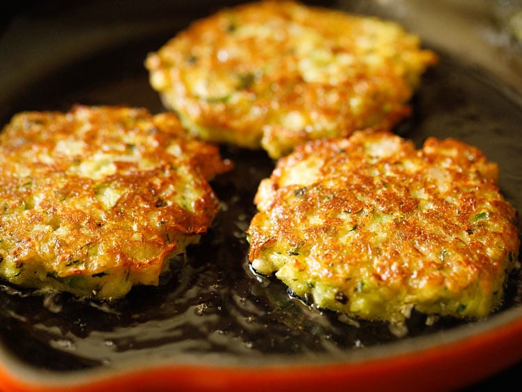 zucchini fritters turned over when one side is golden and crisp.