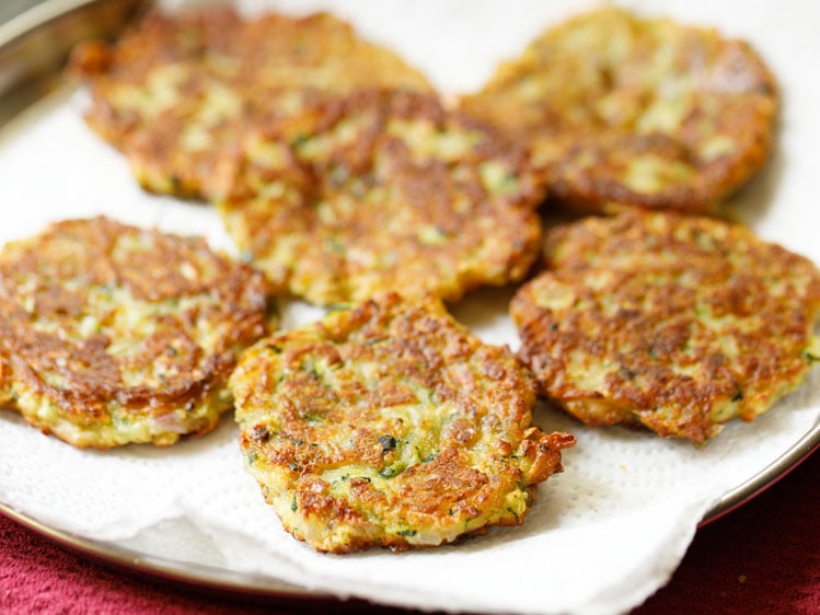 fried crispy zucchini fritters draining on kitchen paper towels.