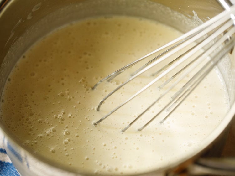 whisk mixing together buttermilk and homemade coconut paste for kerala moru curry